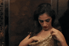 a woman in a gold dress is holding a red item