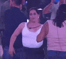 a woman in a white tank top is dancing in a club .