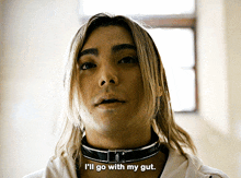 a man with long blonde hair is wearing a choker and says i 'll go with my gut
