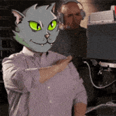 a man with a cat mask on his head stands in front of a computer monitor