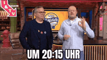 two men are standing next to each other on a stage in front of a sign that says um 20 15 uhr .