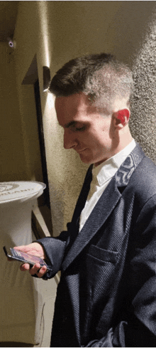 a man in a suit holds a cell phone in his right hand