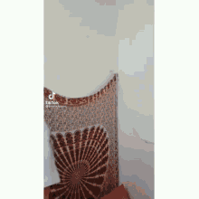 a red and white tapestry is hanging on a wall next to a chair .
