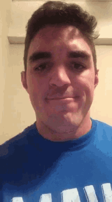 a man wearing a blue shirt with the letter a on it is smiling