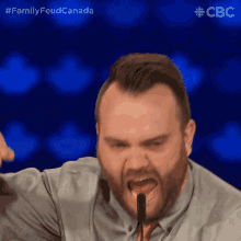 a man with a beard is yelling into a microphone with the hashtag familyfeud canada on the bottom
