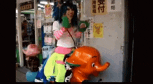 a woman riding on the back of an orange elephant statue