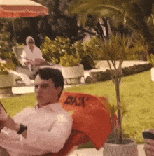 a man is sitting in a chair with an orange towel that says ' bar ' on it