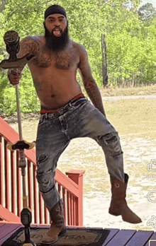 a shirtless man with a beard is standing on a deck holding a lawn mower