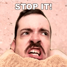 a man with a beard and mustache is buried in sand with the words `` stop it '' above him .