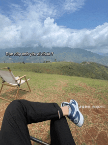 a person sitting on a grassy hill with a chair in the background and a caption that says dao nay anh yeu ai chua