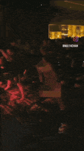 a group of people are dancing in a dark room with a sign that says @ neet4chan