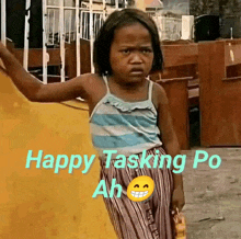 a little girl is standing in front of a yellow wall with the words happy tasking po ah on it