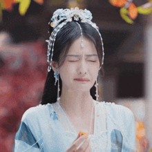 a woman in a blue dress with pearls on her head is making a sad face