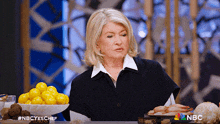 a woman sitting at a table with a bowl of lemons and a plate of shrimp on it