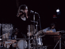 a man is playing a flute in front of a microphone with a keyboard in the background