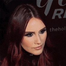 a woman with red hair stands in front of a sign that says " the holl "