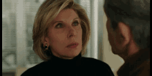 a woman wearing a black turtleneck looks at a man