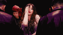 a woman in a white dress is surrounded by purple men