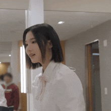a woman wearing a white shirt and a pink bow tie is standing in front of a mirror