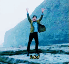 a man is standing on a rock with his arms in the air and says i do !