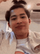 a young man with a bun on his head is making a face .