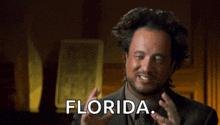 a man in a suit and tie says florida in a dark room