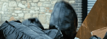 a person in a hooded jacket laying on a pile of garbage bags