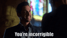 a man in a suit is talking to another man and says you 're incorrigible