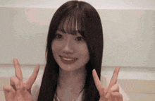 a young woman is making a peace sign with her hands and smiling .