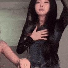 a woman with long black hair is holding her hands on her chest .