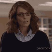 a woman wearing glasses and a black sweater with peacock written on the bottom