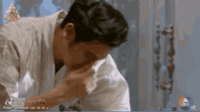 a man wipes his nose in front of a sign that says news
