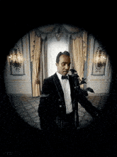 a man in a long black coat stands in a room