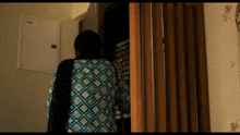a woman in a blue and black shirt stands in a room