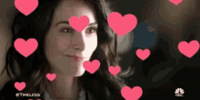 a woman is surrounded by pink hearts and smiling .