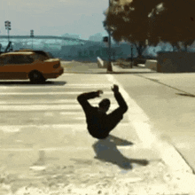 a man is doing a trick on a sidewalk in front of a yellow car