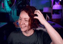 a woman with red hair is smiling in front of a shelf that says n7 on it