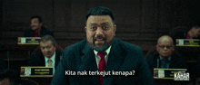 a man in a suit and tie says kita nak terkejut kenapa in front of a group of men