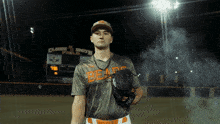 a baseball player wearing a bears jersey stands in front of a scoreboard