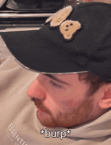 a man wearing a black hat with a bear on it says * burp *