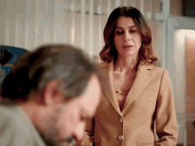 a woman in a tan suit is standing next to a man