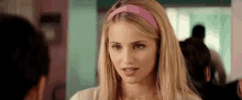 a woman with blonde hair and a pink headband is talking to a man .