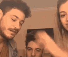 a group of people are standing next to each other in a living room and a woman is holding a man 's head .