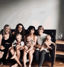 a group of women are sitting on a couch holding baby 's