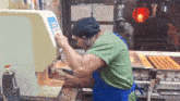 a man in a green shirt is working in a kitchen with a machine that says " suzuki " on it