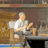 a man is sitting in a chair in front of a sign that says carpark