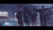 a group of people are standing next to each other in a dark room in front of a car .