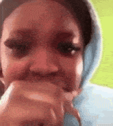 a close up of a woman 's face with a hoodie on covering her mouth .