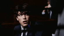 a man in a suit and tie is holding a pen to his mouth .