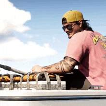 a man wearing a pink shirt that says ' zz ' on the back sits on a boat